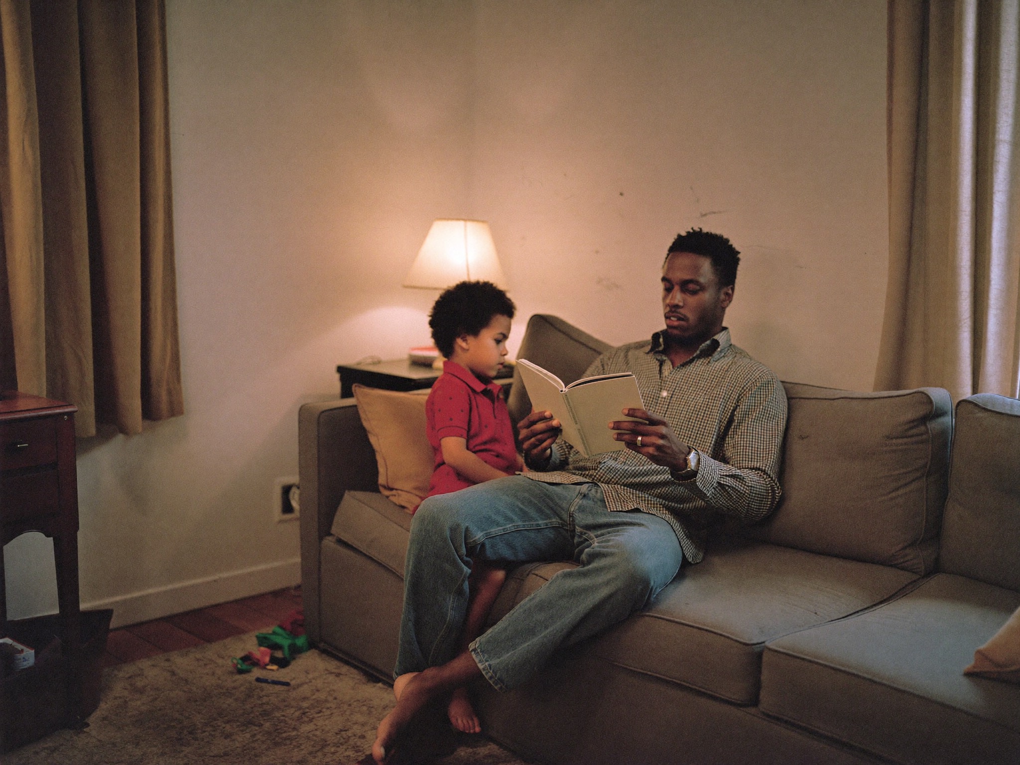 Young father reading with his daughter on a sofa in their living room